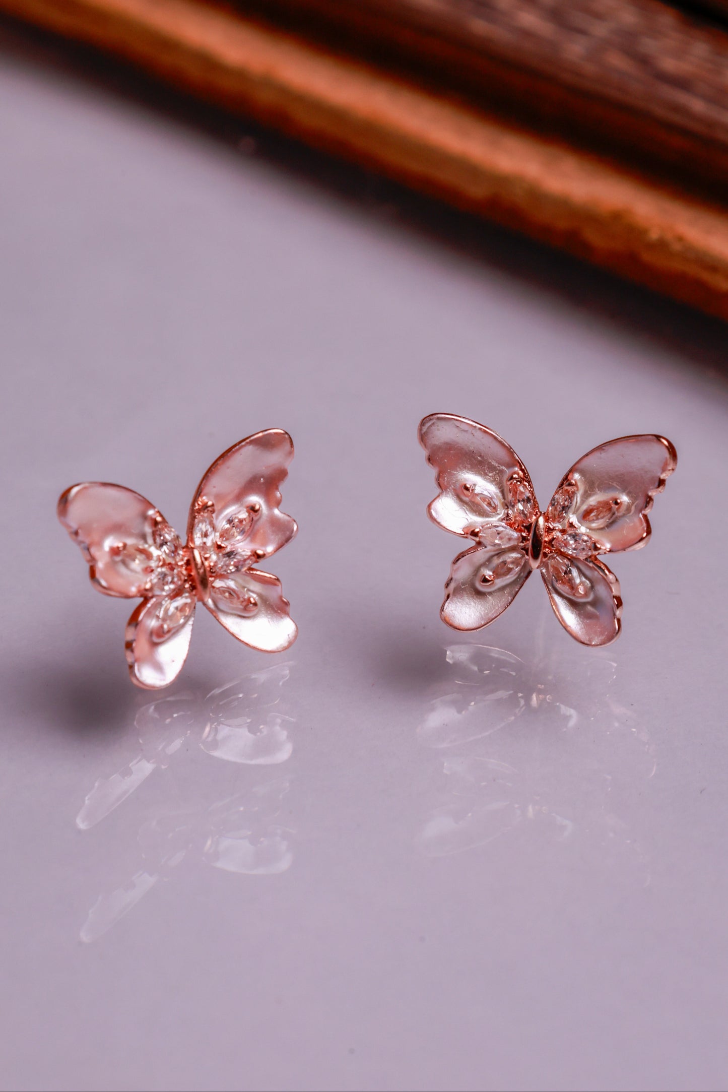Rose gold butterfly earrings with detachable pearl drop chain on white background