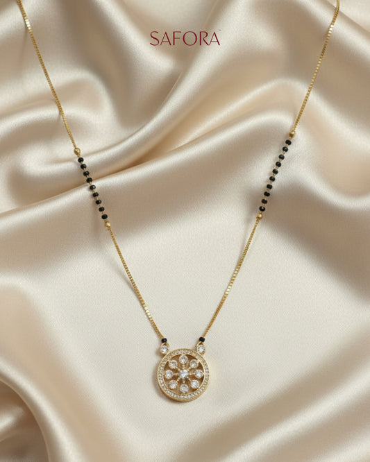 Gold necklace with a pendant on a beige fabric background, featuring the brand 'SAFORA'.