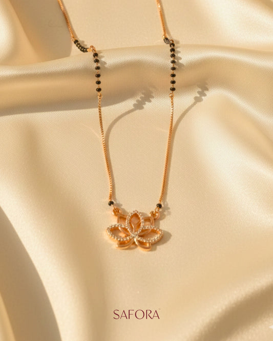 Gold necklace with a pendant on a beige fabric background, featuring the brand 'SAFORA'.
