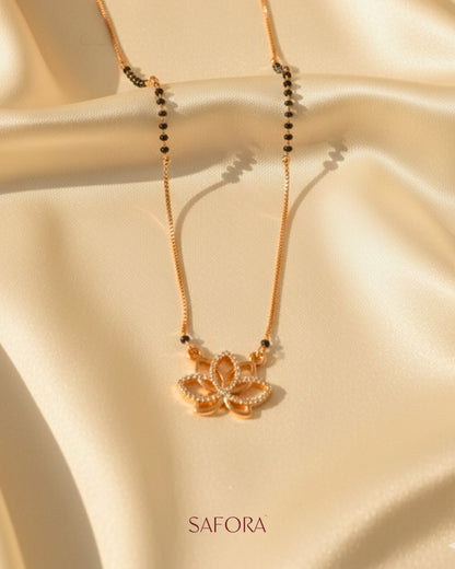 Gold necklace with a pendant on a beige fabric background, featuring the brand 'SAFORA'.