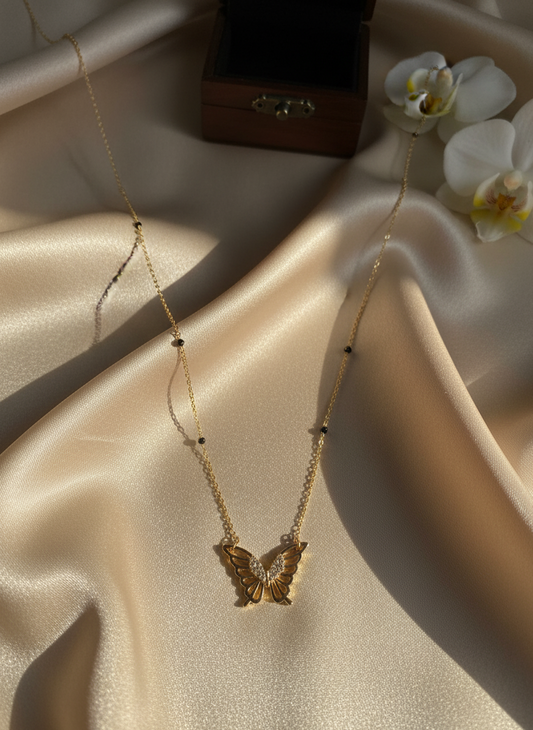 Gold butterfly necklace on a beige fabric background with flowers