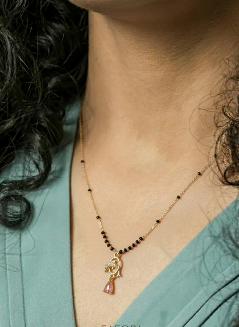 Necklace with a pendant worn by a person, brand 'SAFORA' visible