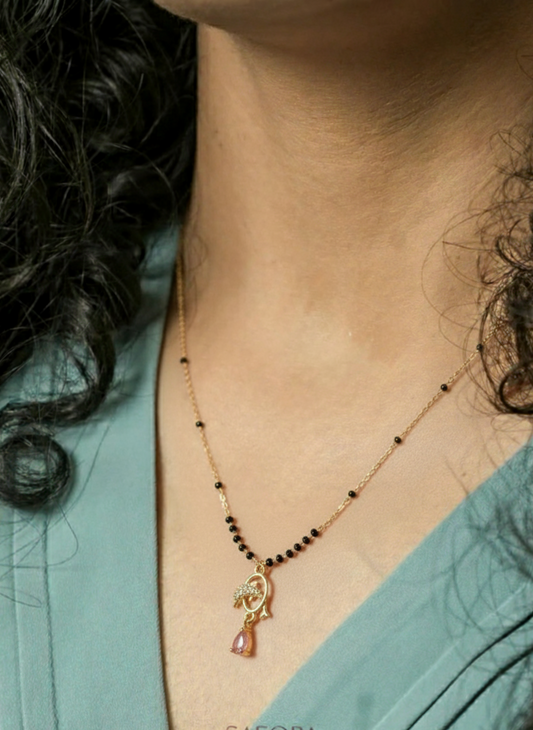 Necklace with a pendant worn by a person, brand 'SAFORA' visible